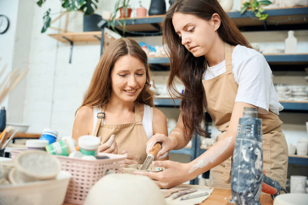 istock Women artisans handcrafting carving pottery in ceramics studio with tools 2083087333