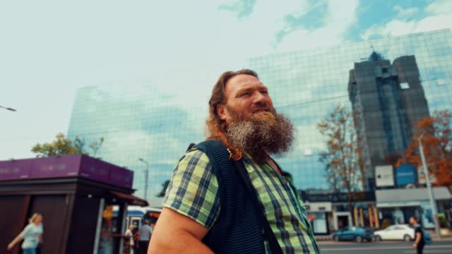 Red bearded elderly man stands in the square and looks at the sky