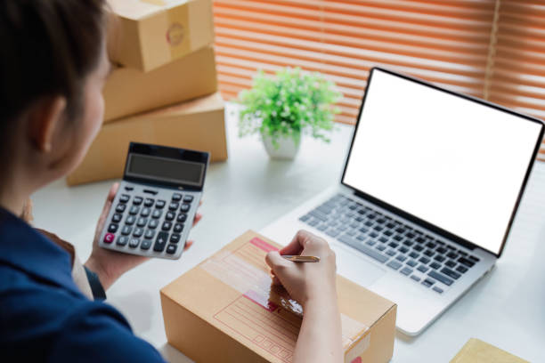 istock Entrepreneur using calculator in her hand, calculating financial expense at home office, online market packing box delivery 2083139532