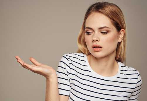 indignant blonde on beige background in striped t-shirt model cropped view. High quality photo