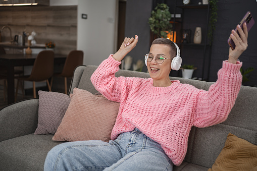 Caucasian woman with short hair having fun listening to music at home.