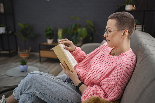 Caucasian woman with short hair at home reading a book.