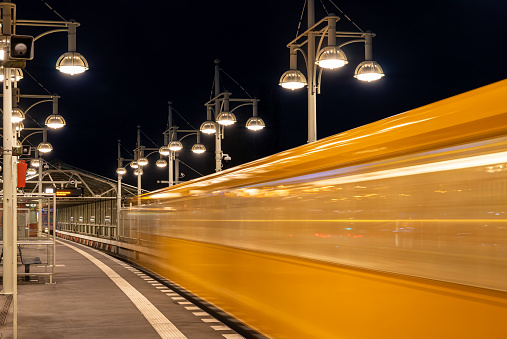Germany, Berlin, March 06, 2024 - Blurred motion of subway train arriving subway station  at night, Berlin Friedrichshain Warschauer Strasse
