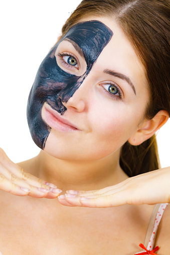 Woman with clay carbo detox black mask on her face, on white. Girl taking care of oily skin complexion. Beauty treatment. Skincare.