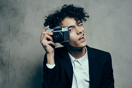 photographer with a camera in a classic suit curly hair Studio Model. High quality photo