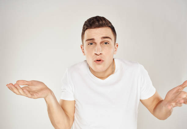 istock Surprised man spreads his hands to the sides on a light background cropped view 2083280425