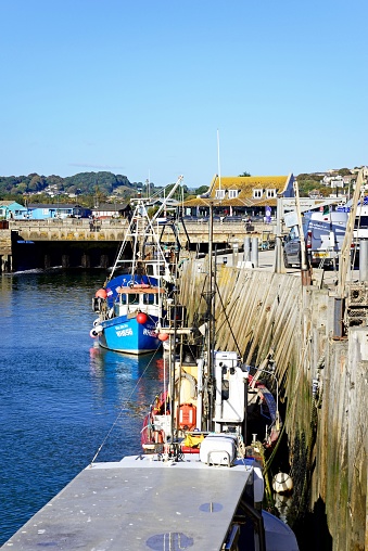 Fishing boats moored in the harbour with the sluice gate and town buildings to the rear, West Bay, Dorset, UK, Europe.