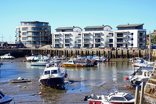 Fishing boats moored in the harbour with the Ellipse building and apartments to the rear, West Bay, Dorset, UK, Europe.