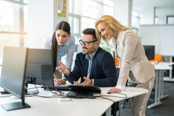 istock Group of three business partners discussing documents and reports on computer in modern office. 2083308409