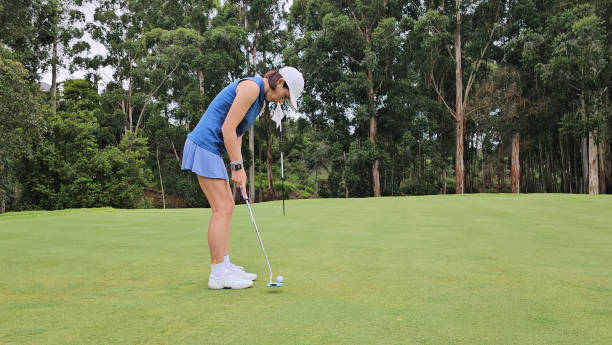 istock woman golf player putting on green with lake 2083310048