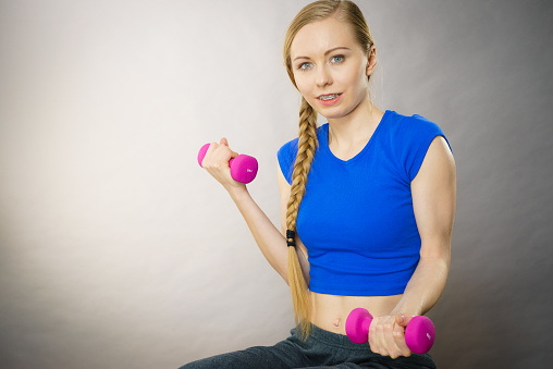 Teenage young woman working out at home with small light dumbbells. Training at home, being fit and healthy.