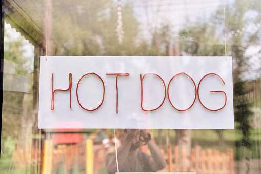 Hanging sign with hot dog written behind glass. High quality photo