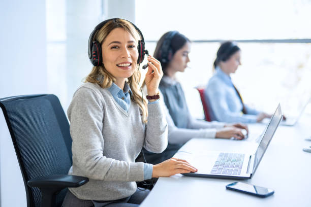 istock Woman operator agent with headsets and her team working in a call center customer service office 2083312729