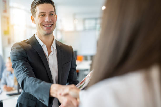 istock Handsome businessman with braces smiling while shaking hands with female company manager ready for job interview. 2083328509