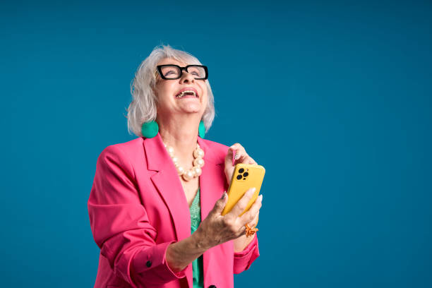 istock Joyful Senior Lady Laughing while Holding a Smartphone 2083329030