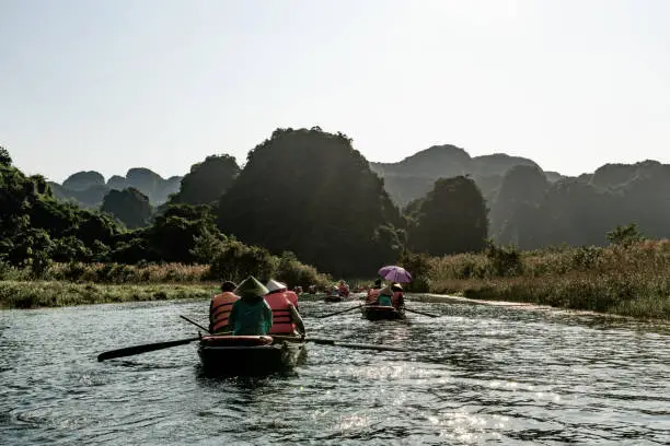 Photo of Tourists float down a river amid limestone mountains in Tam Coc, northern Vietnam.
