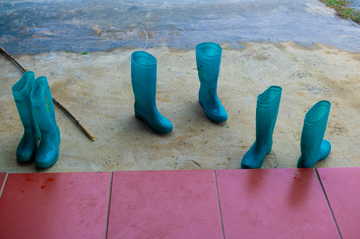 Still life of red tiles and three pairs of blue, rubber, waterproof boots worn by Hmong women who guide treks through the damp and muddy mountain region of northern Vietnam.