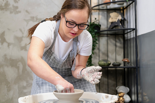 Young woman with Down Syndrome working at pottery workshop