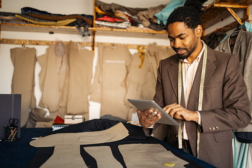 African American man using digital tablet at his tailoring shop