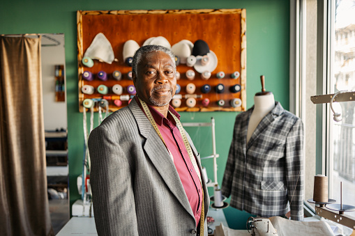 Latin senior man owner of a small tailoring business. Active senior with gray hair working