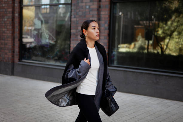 stylish fashion woman strolls down the street in multilayer clothes oversized blazer, black leggings. fashionable outfit, street style - blazer women black leggings стоковые фото и изображения