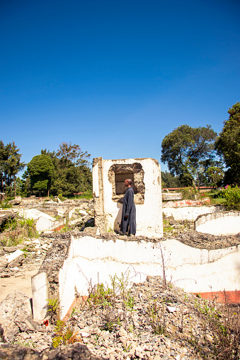 A young african woman standing amongst  the rubbles ona demolished house in the countryside