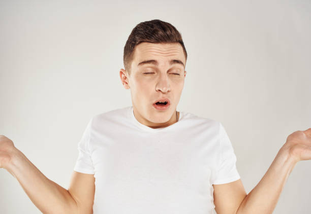 istock A guy in a white T-shirt gestures with his hands on a light background emotions model cropped view 2083391239