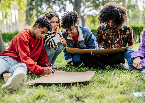 Group of young adults collaborating on a project in a peaceful park setting.
