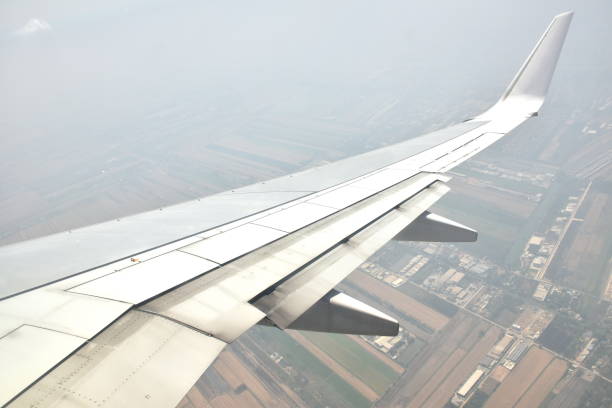 plane wing and city background on sky through window frame on sunny day