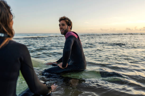 istock Friends on surfboards sitting in the ocean and having fun. 2083397265