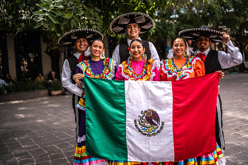 Portrait of dancers holding Mexican flag outdoors