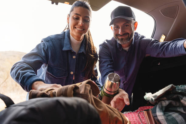 istock Couple preparing for a picnic, while taking a backpack and thermos from the car trunk 2083436593