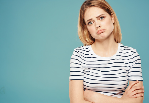 Woman model in striped t-shirt indignant look emotions blue background. High quality photo