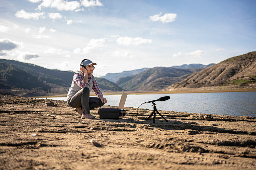 Sustainability practices. Woman does field-based studies using AI driven ecoacoustic approaches in bioacoustics research.