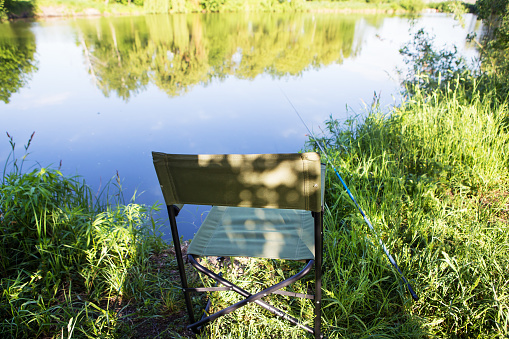 Armchair for fishing on the lake. Fishing rod in the water.