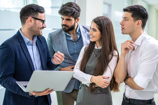 Divided diverse group of business people commenting a company's goals and ambitions, along with the timeline, finances, and methods needed to achieve them on laptop in the office.