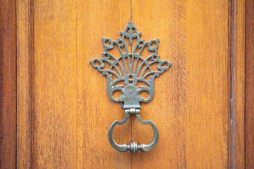 Traditional brass door knocker on a red door in Meknes, Morocco.