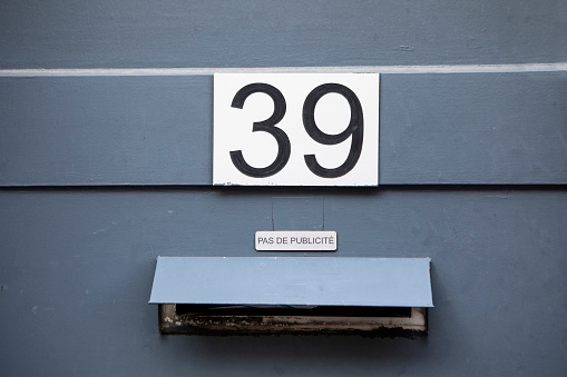 Enameled house number sixteen, attached on a wooden plank.
