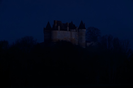 Close-up of Château de Bannes, a magnificent medieval castle in the Dordogne, at sunrise on the blue hour.