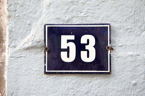 Weathered grunge square metal enameled plate of number of street address with number 29 closeup