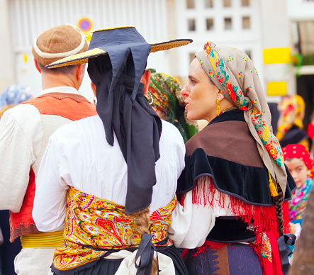 Rear view of folk dressed up women  multicolored folk traditional clothing in old town Lugo city, Galicia, Spain during San Froilán traditional celebrations.