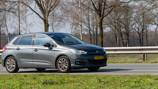 Netherlands, Overijssel, Twente, Wierden, March 19th 2023, side/front view close-up of a 2013 Dutch gray Citroën 2nd generation C4 hatchback driving on the N36 at Wierden, the C4 has been made by French manufacturer Citroën since 2004, the N36 is a 36 kilometer long highway from Wierden to Ommen