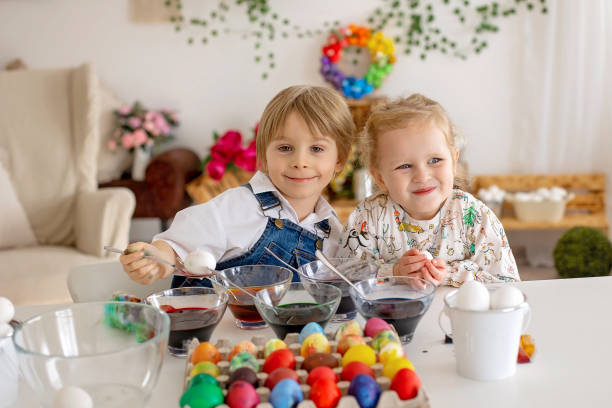 istock Happy children, siblings, coloring eggs for Easter at home, sunny room 2083528829