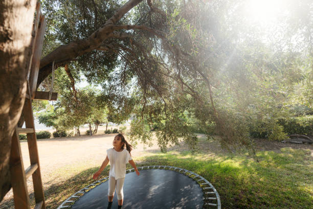 Active female athlete performing a jump in nature, focusing on fitness and outdoor exercise against a scenic rural background