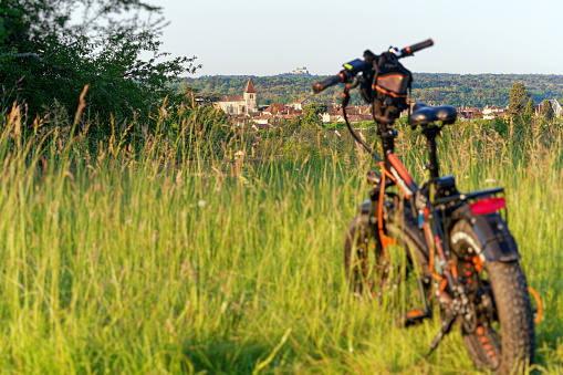 An electric bike in a field to admire the view of Monpazier and Château de Biron. Dordogne, Nouvelle-Aquitaine, france