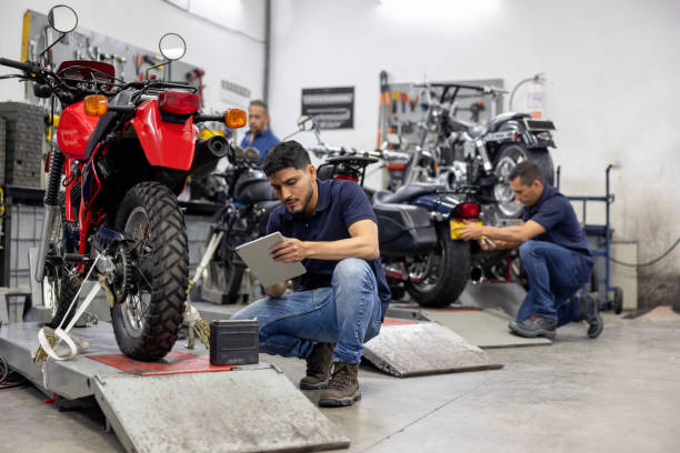 istock Mechanic checking the battery level on a motorcycle and using a digital tablet 2083542226