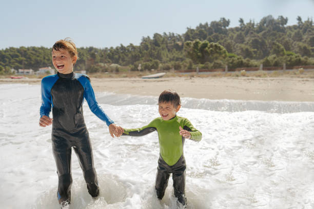 Photo of young boys rushing into the sea water and having fun on the waves