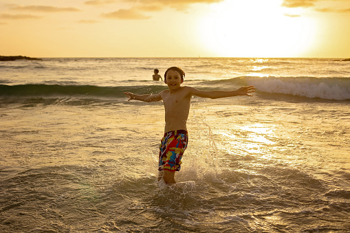 Happy teenager boys, running and playing on the beach on sunset, splashing water and jumping on the sand. Tel Aviv, Israel