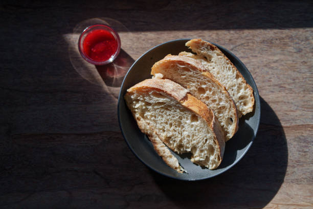 High angle view a plate of sourdough bread with strawberry jam is placed on a table, with morning sunlight shining on it.