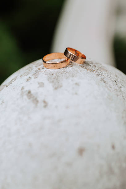 istock Gold classic wedding rings on white round ball and blurred forest or park background 2083573521